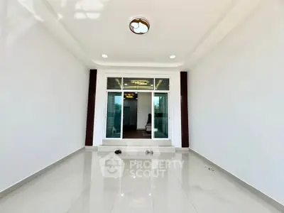 Spacious modern interior with sleek white tiles and glass doors, perfect for versatile living space.