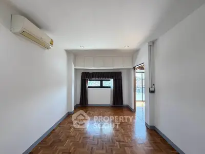 Spacious empty room with parquet flooring and air conditioning, perfect for customization.