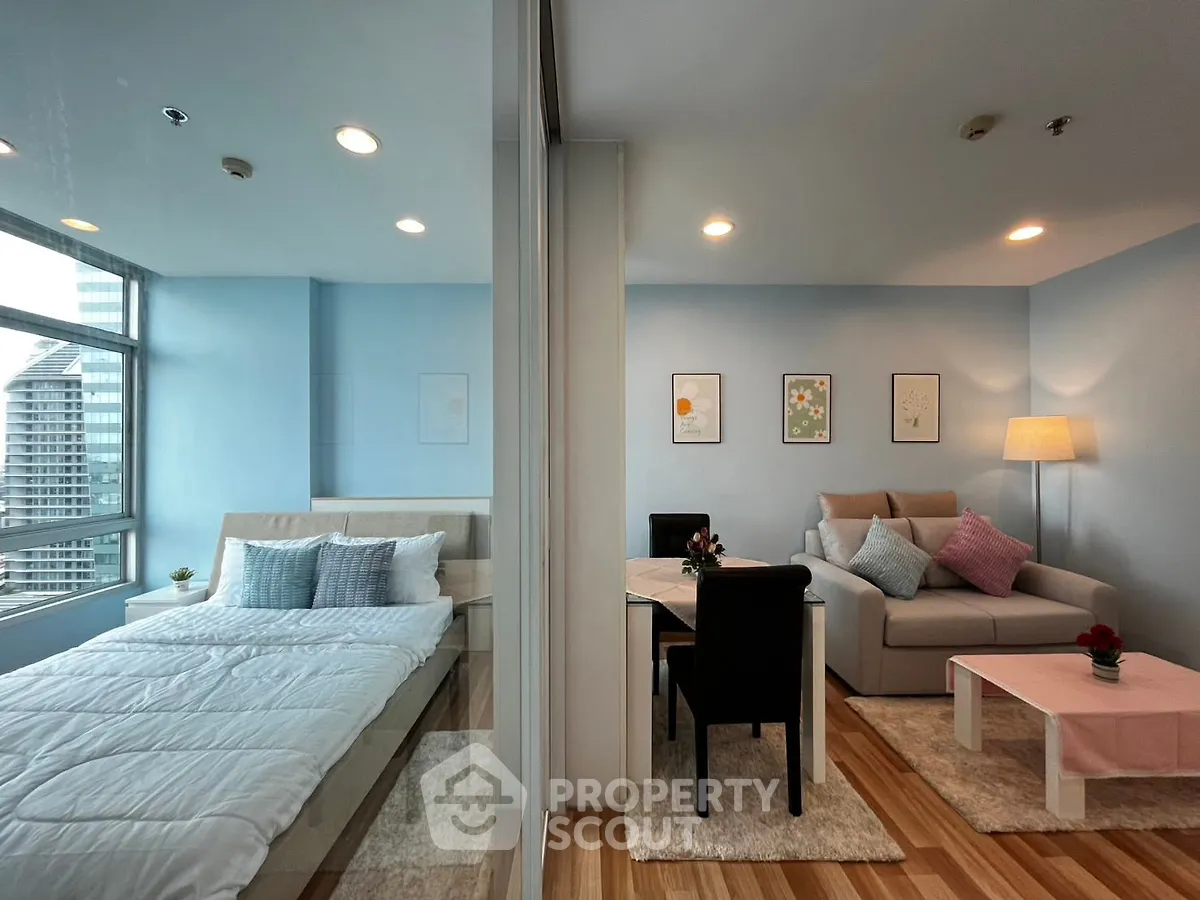 Modern open-plan living room and bedroom with stylish decor and city view.