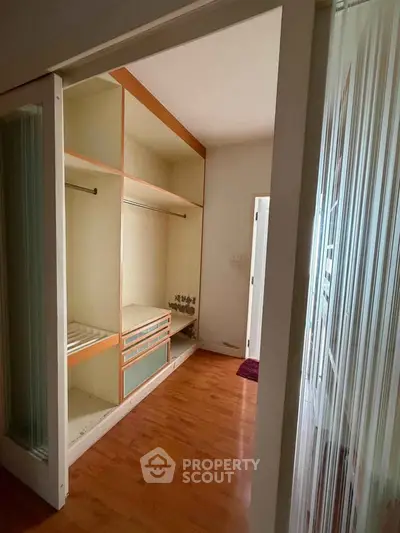 Spacious walk-in closet with wooden flooring and ample storage space.