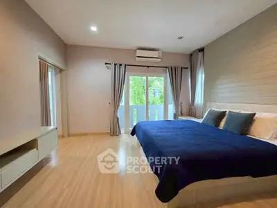 Spacious bedroom with large bed and natural light from balcony view.