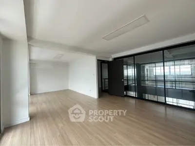 Spacious modern living room with wooden flooring and glass partition