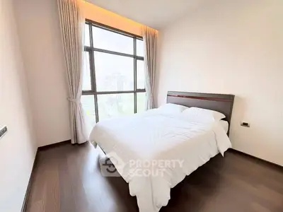 Bright and cozy bedroom with large window and elegant curtains in modern apartment.