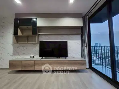 Modern living room with sleek TV unit and large balcony offering city views.