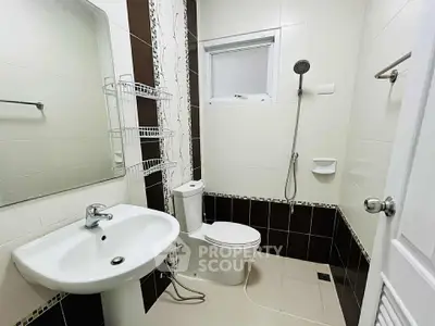 Modern bathroom with sleek fixtures and neutral tiles, featuring a shower and toilet.