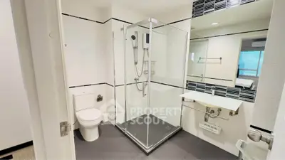 Modern bathroom with glass shower and sleek fixtures in contemporary apartment.
