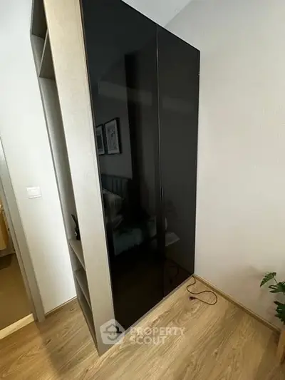 Modern bedroom with sleek black wardrobe and wooden flooring
