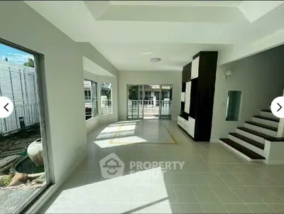 Spacious living room with large windows and modern design, offering abundant natural light and garden view.