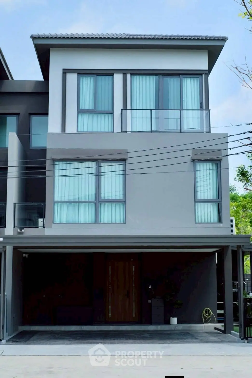 Modern three-story townhouse with sleek design and large windows in a suburban neighborhood.