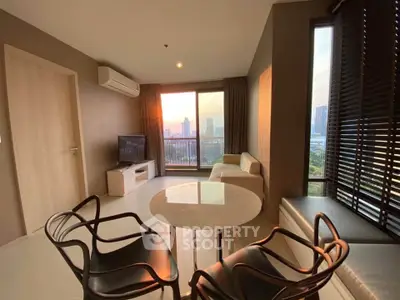 Modern living room with city view, featuring stylish furniture and large windows for natural light.