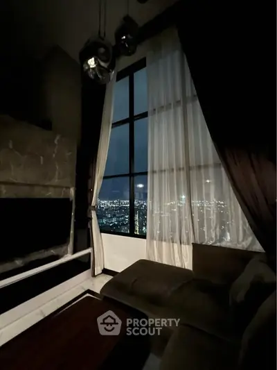 Luxurious living room with stunning city view through large windows, elegant decor and cozy ambiance.