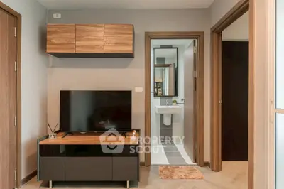 Modern living area with sleek TV stand and bathroom view, showcasing contemporary design.