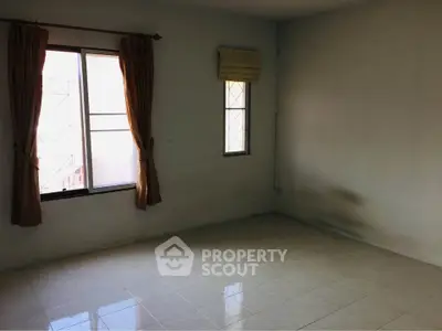 Spacious empty room with tiled floor and large windows, perfect for customization.