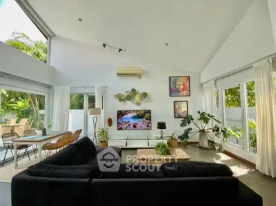 Spacious living room with modern decor and large windows offering lush garden views.