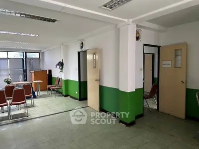 Spacious office space with green accents and ample natural light, ideal for meetings and collaborative work.