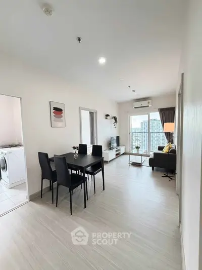 Modern living room with dining area and city view, featuring sleek furniture and bright natural light.