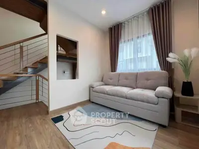 Modern living room with stylish sofa and wooden staircase, featuring elegant decor and natural light.
