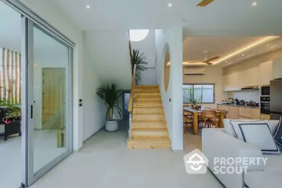 Modern open-plan living room with wooden staircase and stylish kitchen area.