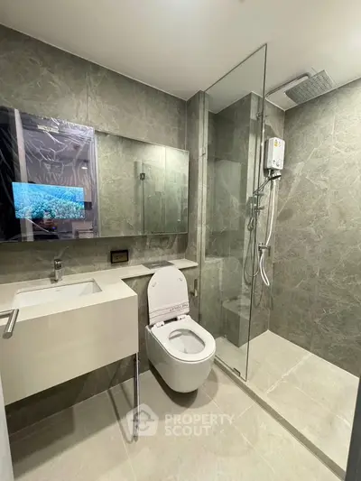 Modern bathroom with glass shower and sleek fixtures in luxury apartment.