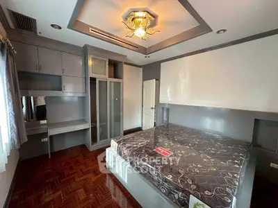 Spacious bedroom with modern built-in storage and elegant ceiling light fixture.