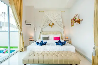 Luxurious bedroom with elegant decor and pool view, featuring plush bedding and stylish curtains.