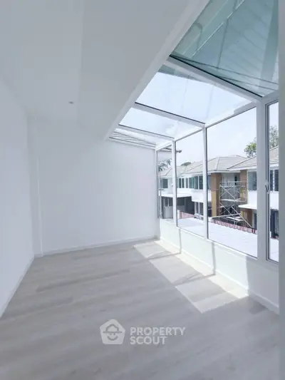 Bright sunlit room with large windows and modern flooring, ideal for a serene living space.