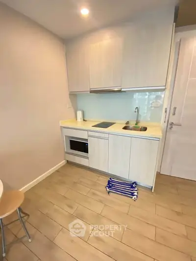Modern compact kitchen with sleek cabinetry and built-in appliances in a cozy apartment.