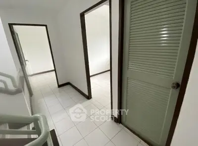 Spacious hallway with white tile flooring and green doors in a modern home.