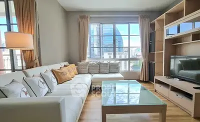 Spacious living room with modern decor and city view, featuring a cozy sectional sofa and entertainment center.
