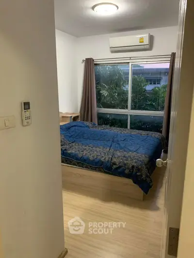 Cozy bedroom with large window and air conditioning, perfect for relaxation.