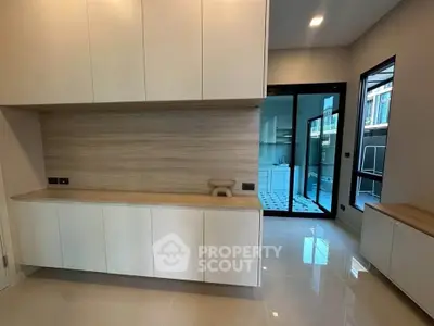 Modern kitchen with sleek cabinetry and open layout, featuring glossy tile flooring and ample natural light.