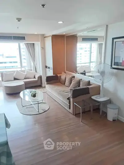 Spacious living room with modern decor and large windows offering city views.