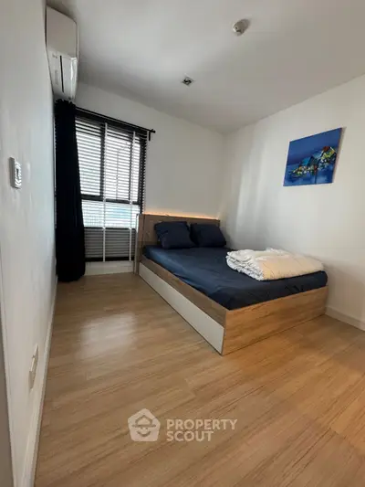 Cozy bedroom with modern decor and natural light, featuring a comfortable bed and stylish wooden flooring.