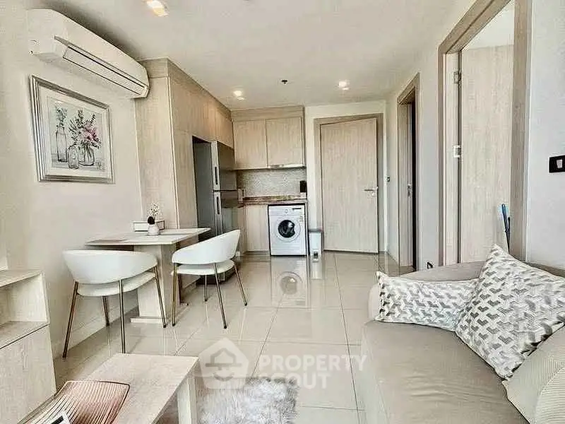 Modern apartment interior with open kitchen and cozy living area, featuring stylish furniture and appliances.