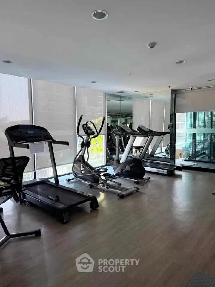 Modern gym with treadmills and exercise equipment in a well-lit space with large windows.