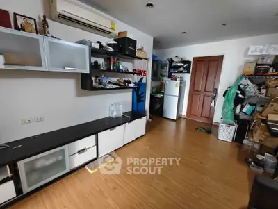 Spacious living room with modern shelving and wooden flooring, featuring a refrigerator and ample storage space.