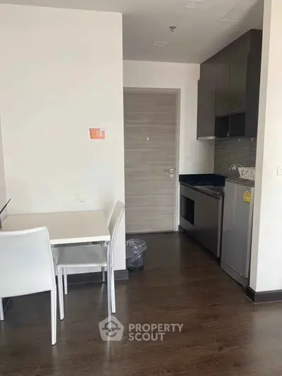 Modern kitchen with sleek cabinetry and dining area in contemporary apartment.
