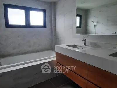 Modern bathroom with sleek design, featuring a bathtub and double sink vanity.