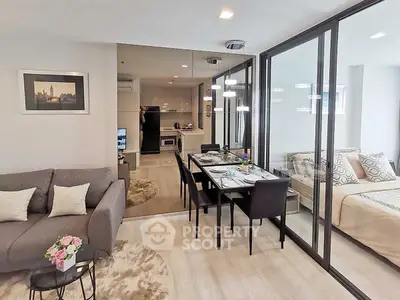 Modern open-plan living room with dining area and bedroom, featuring sleek furniture and stylish decor.