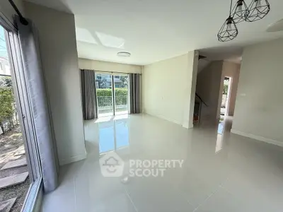 Spacious living room with large windows and modern lighting in a bright, open layout.