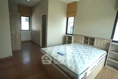 Spacious bedroom with wooden flooring and large windows in modern apartment