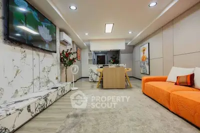 Modern living room with vibrant orange sofa and stylish decor, featuring open layout and elegant marble accents.
