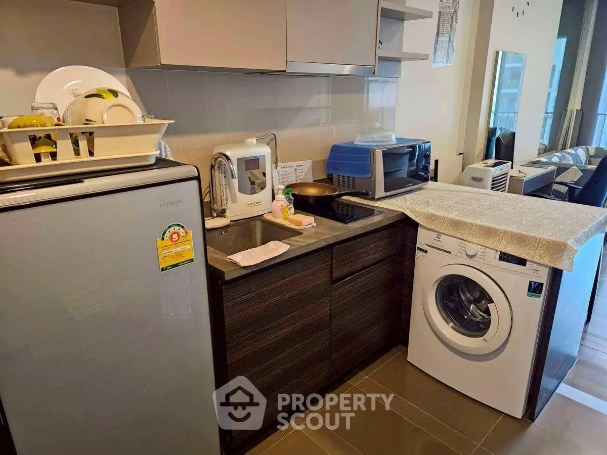 Modern kitchen with appliances including fridge, washing machine, and microwave in compact layout.