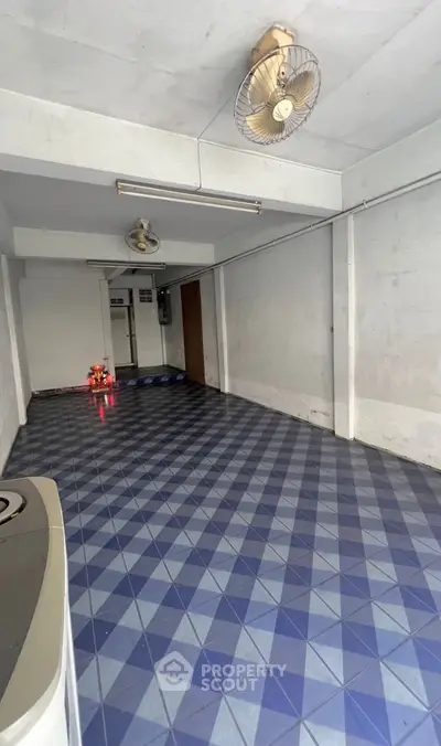 Spacious tiled room with ceiling fans, ideal for versatile use in real estate property.