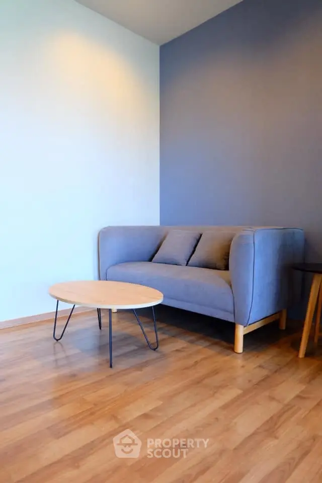 Modern living room with stylish blue sofa and wooden coffee table on elegant flooring.