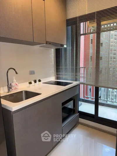Modern kitchen with sleek cabinetry and large window offering natural light.