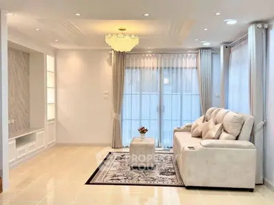 Elegant living room with plush sofa, chic chandelier, and large windows for natural light.