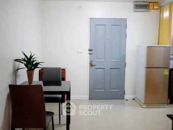 Cozy apartment entrance with dining area and fridge, perfect for modern living.