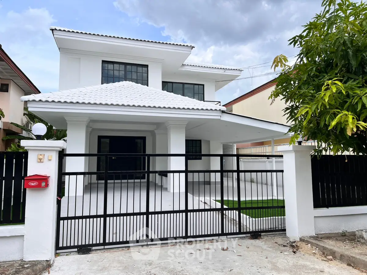 Stunning modern white two-story house with gated entrance and spacious driveway.