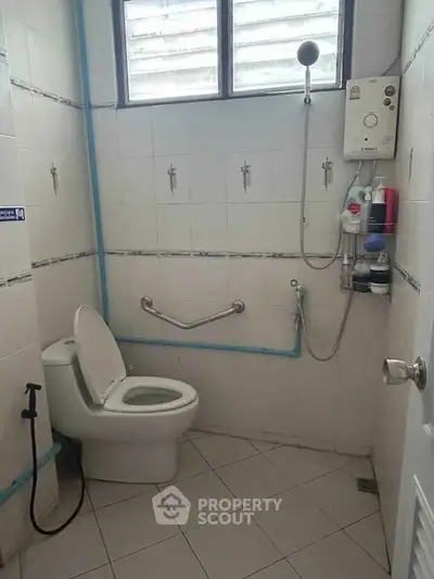 Functional bathroom with shower and toilet in a well-lit space, featuring essential amenities.